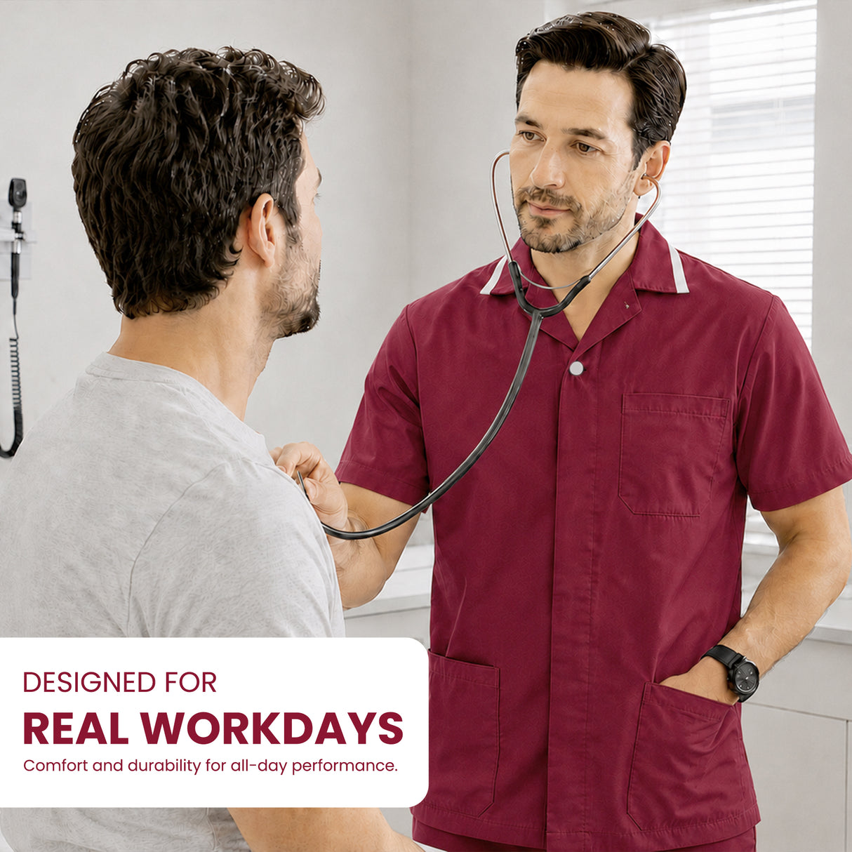 Uk Scrub Supply man in a burgundy short-sleeve medical scrub top with a stethoscope around his neck stands in a clinic examining another man. A text overlay at the bottom left reads 'DESIGNED FOR REAL WORKDAYS Comfort and durability for all-day performance.