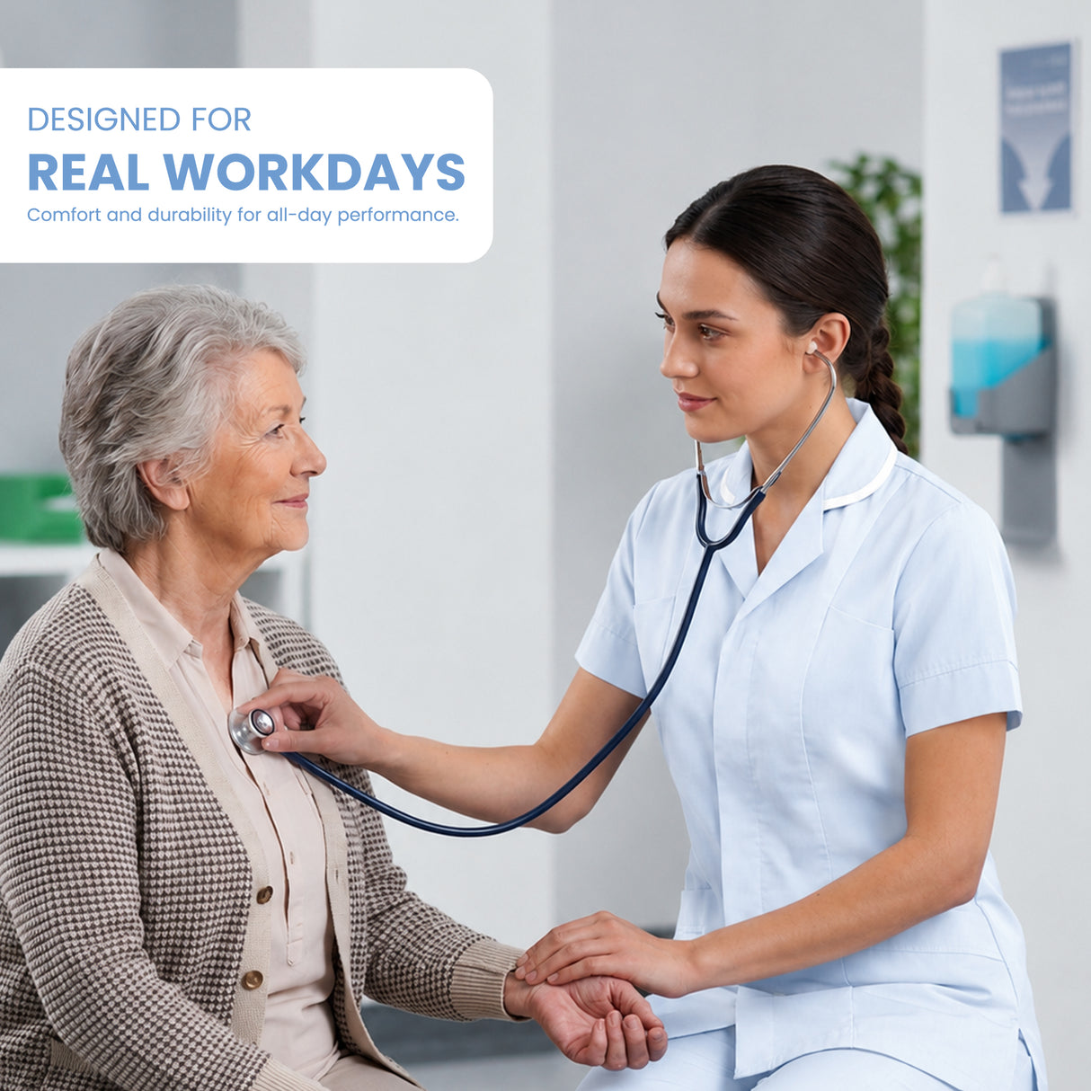 A healthcare worker in light blue scrubs uses a stethoscope on an elderly woman seated nearby in a bright clinic setting. A text overlay in the top left reads, 'DESIGNED FOR REAL WORKDAYS' with smaller supporting text below.