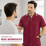 Uk Scrub Supply man in a burgundy short-sleeve medical scrub top with a stethoscope around his neck stands in a clinic examining another man. A text overlay at the bottom left reads 'DESIGNED FOR REAL WORKDAYS Comfort and durability for all-day performance.