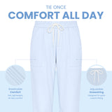 Uk Scrub Supply Light blue drawstring lounge pants centered on a white and pale blue background, with marketing text reading 'TIE ONCE COMFORT ALL DAY' and callout circles highlighting breathable comfort and adjustable drawstring features.