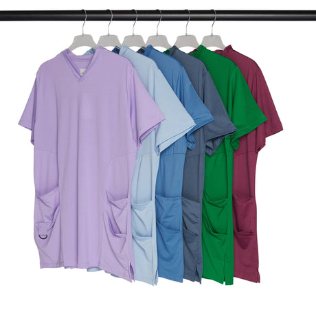 Row of colorful scrub tops on hangers against a white background.