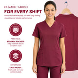 a woman wearing burgundy V-neck scrub tops and matching scrub pants stands against a pale pink background, with a second view of the scrub top on a hanger behind her. Text highlights fabric durability, practical storage pockets, and effortless care fabric.