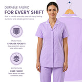 A woman wearing a light purple short-sleeve scrub top and matching pants stands against a pale lavender background, with a second view of the scrub top hanging on a hanger behind her. Text on the left highlights durable fabric, practical storage pockets, and effortless care fabric. Women’s Medical Tunic Nursing & Healthcare Uniform UK scrub tops
scrubs clothing
nursing scrubs
medical uniforms
scrubs for sale
work scrubs
buy medical uniforms
female scrub tops
order scrubs
scrubs to purchase
cheap scrub tops
